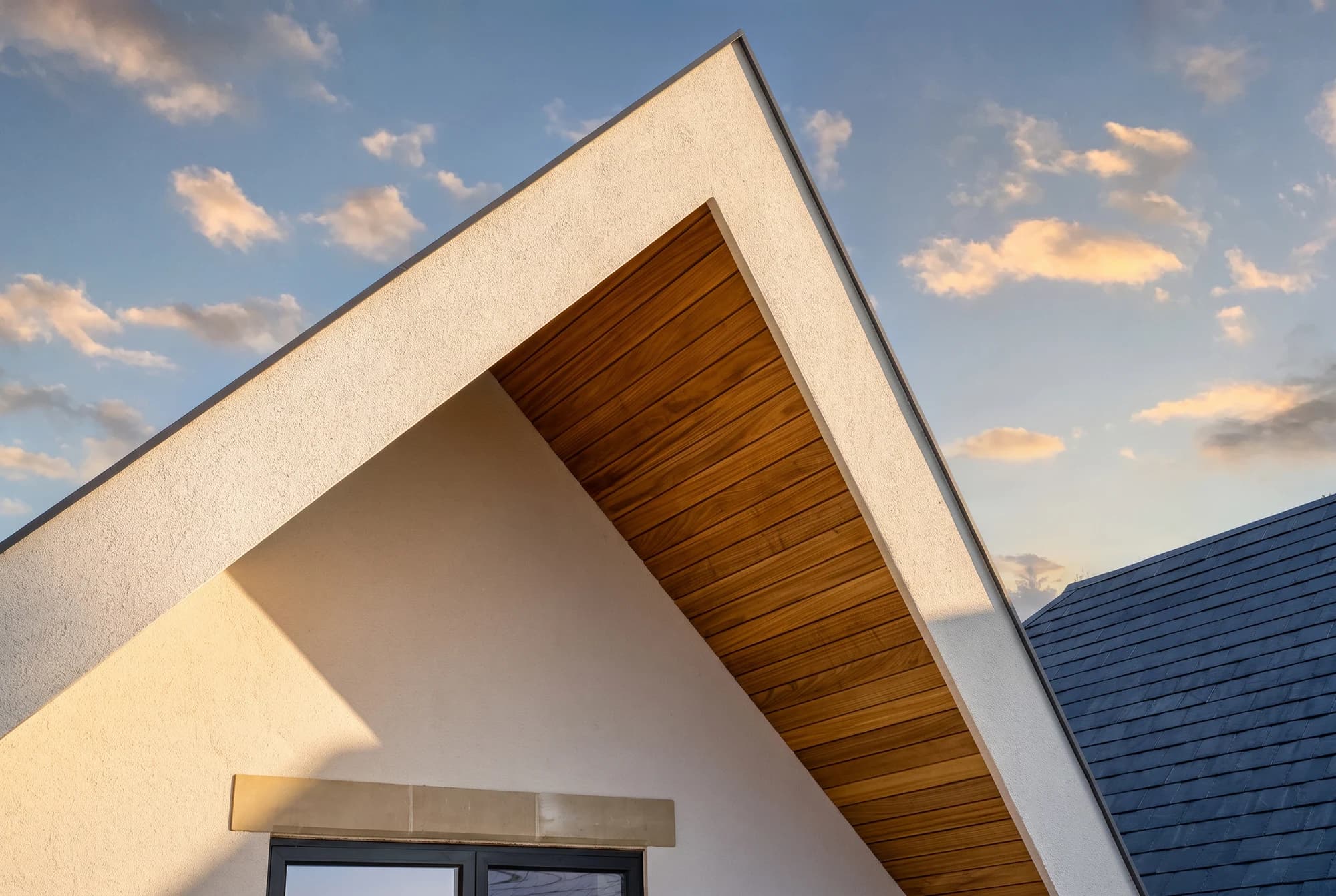 Timber-lined gable and white render against the evening sky