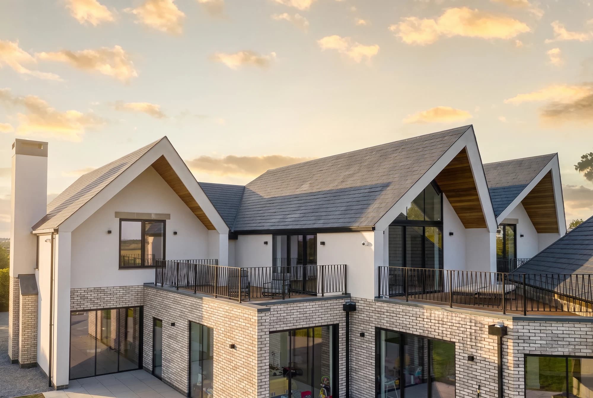 Pitched roofs, pale brick and timber soffits in evening light
