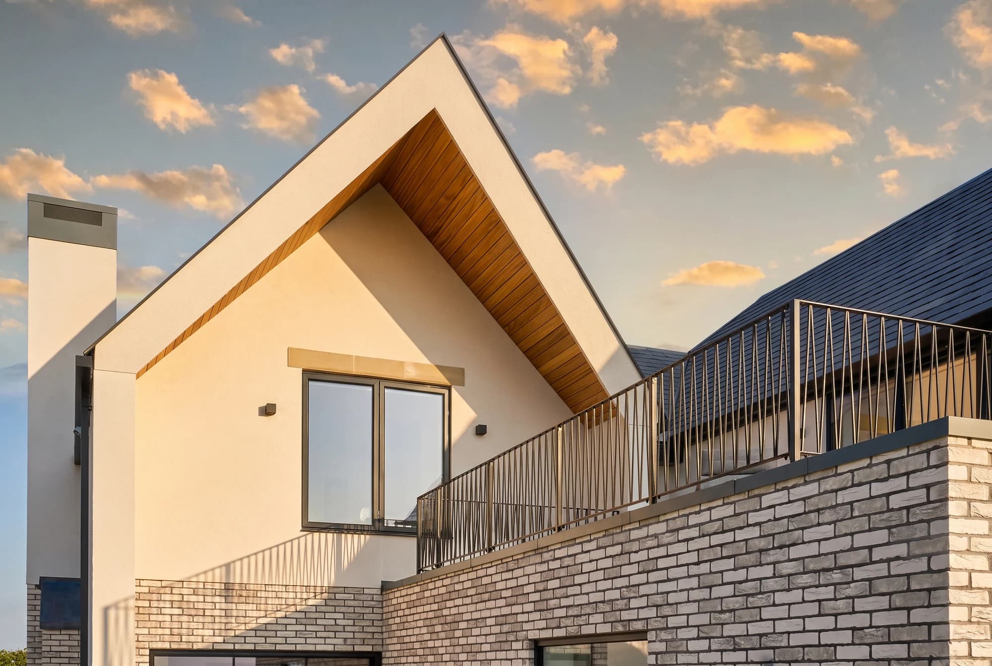 Gabled facade with timber soffits and a pale brick terrace